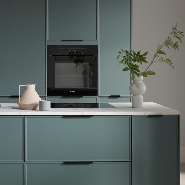 Moderne Einbauküche nach Maß in der Trendfarbe Eukalyptus mit heller Arbeitsplatte.